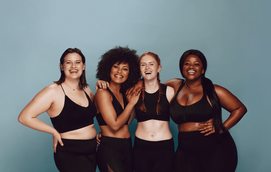 Four women wearing black gym clothes smile at the camera.